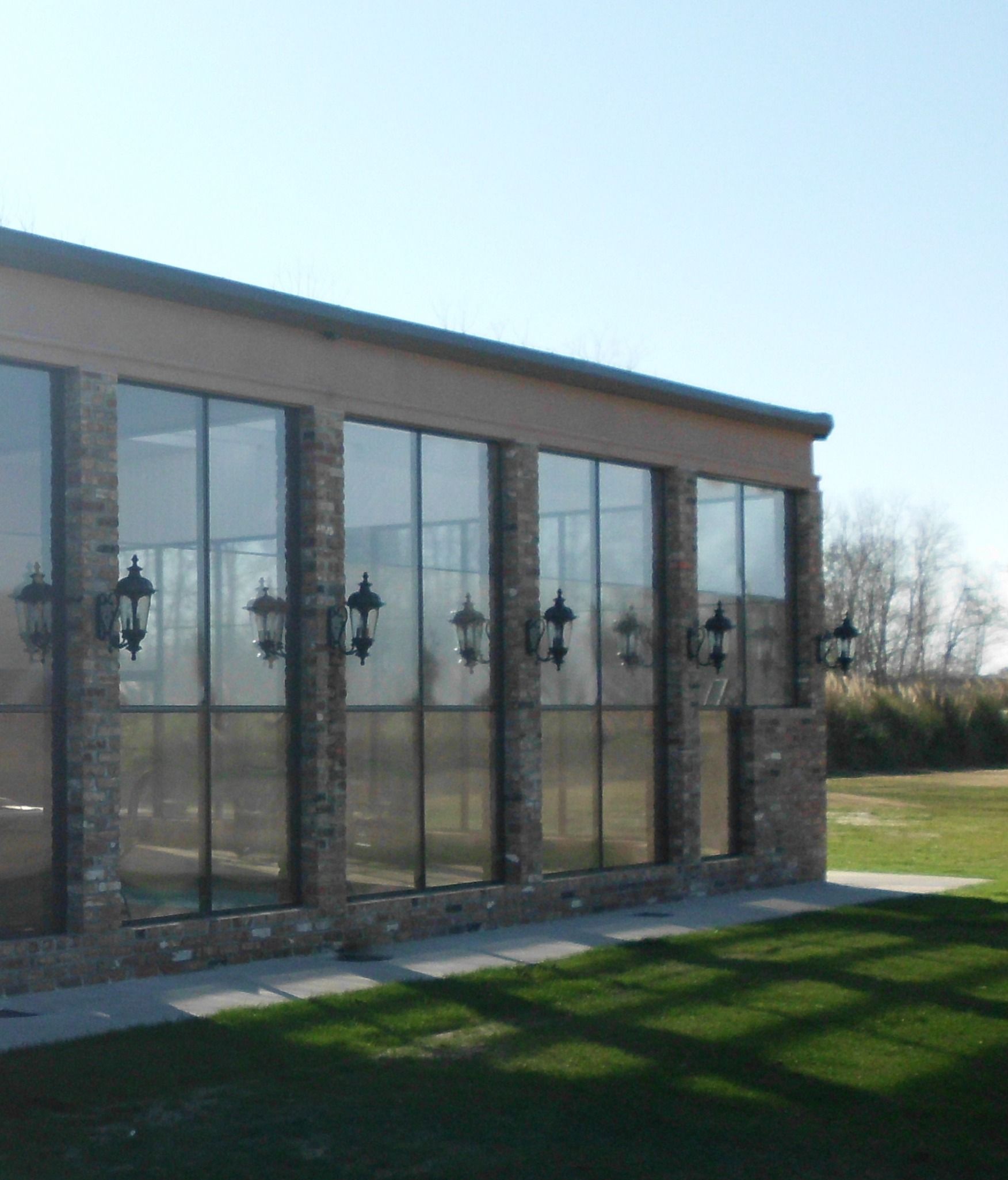 A modern house with a pool and patio overlooking a grassy yard.