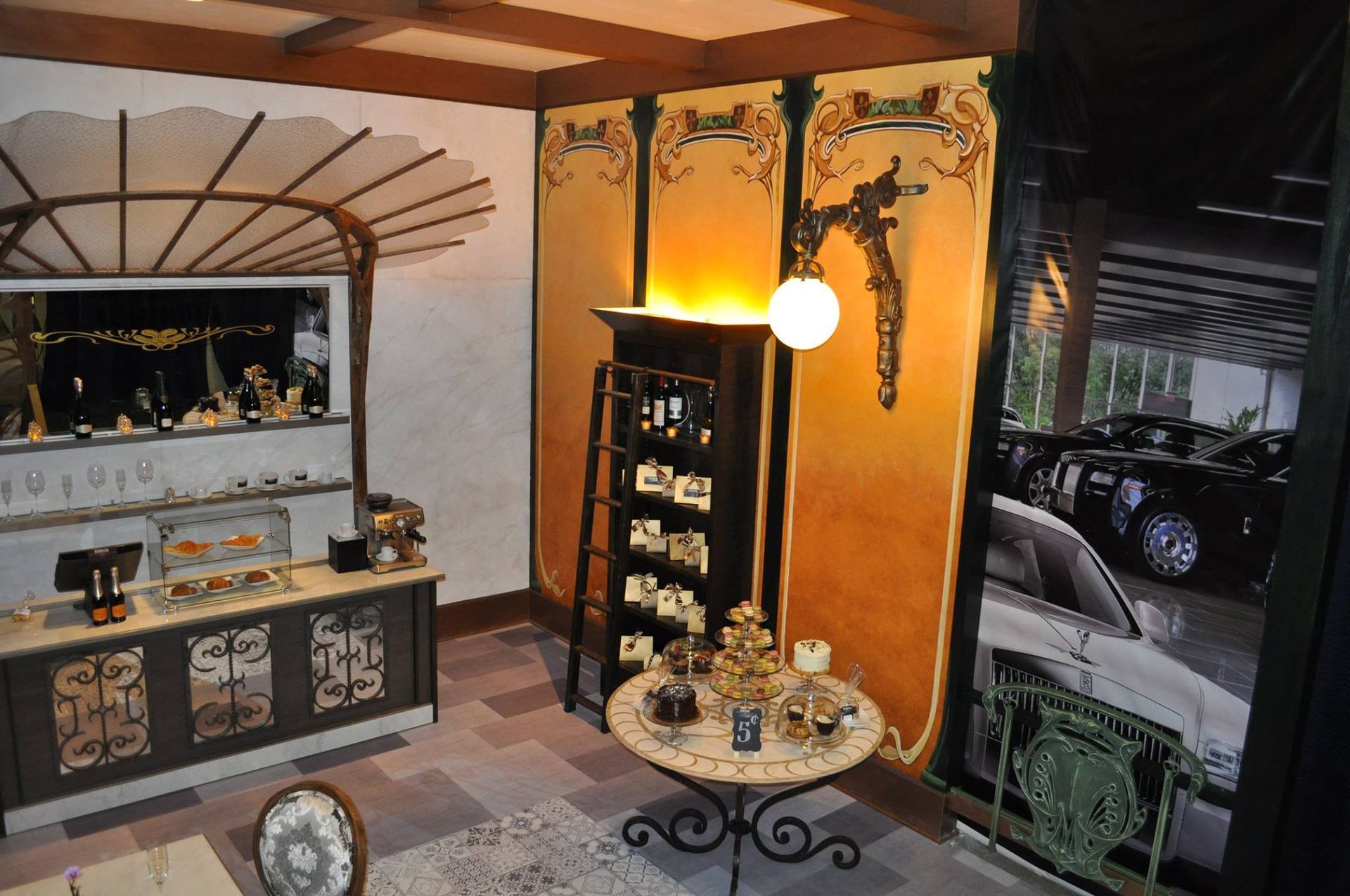Jewelry shop interior with display cases, ornate wall art, and a view of parked cars.