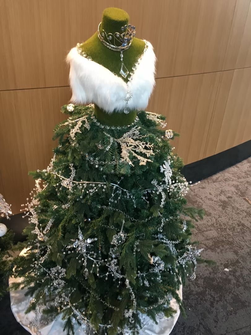 Christmas tree shaped like a dress, with a faux-fur top and decorated with snowy garland and jewelry.