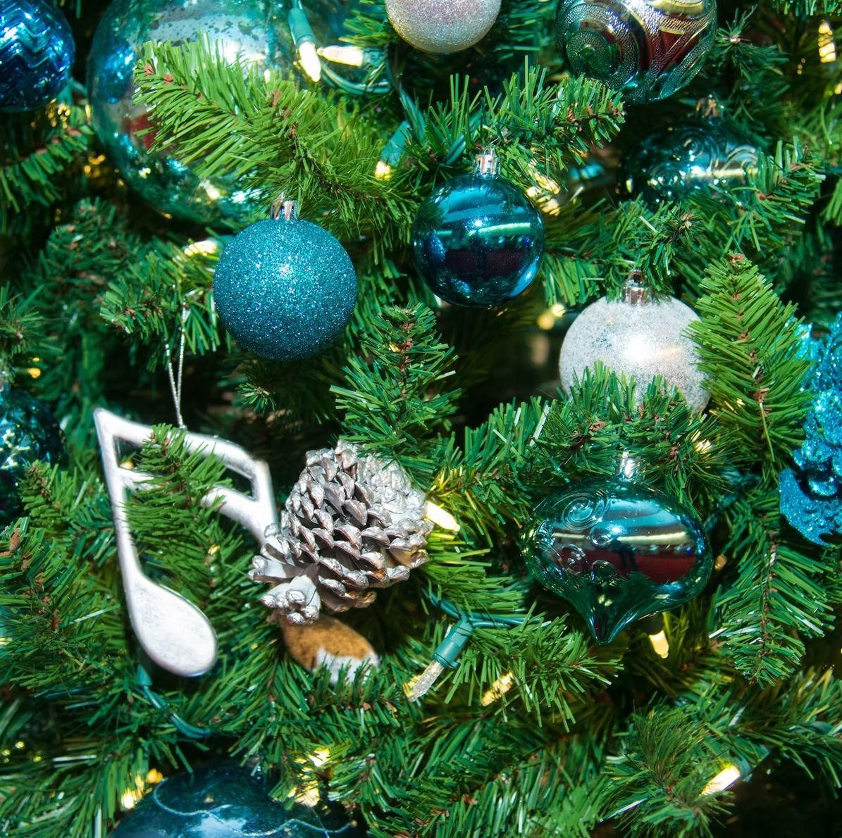 Christmas tree decorated with blue and silver ornaments, pinecones, and musical notes.