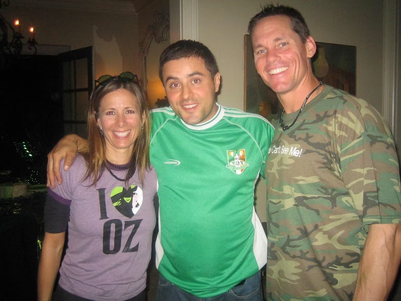 Three people smiling, posing together. Woman in purple 