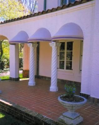 A pink house with white columns and purple awnings