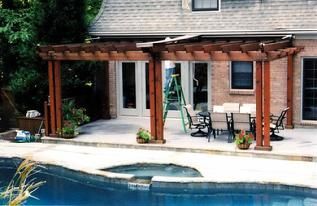 A house with a pergola over a swimming pool.