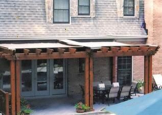 A wooden pergola is sitting in front of a house.