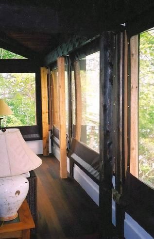 A screened in porch with a lamp on a table