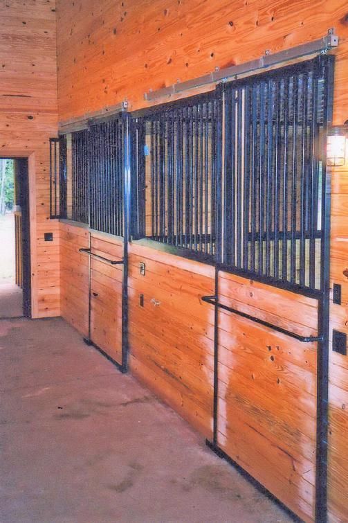A row of wooden horse stalls with metal bars