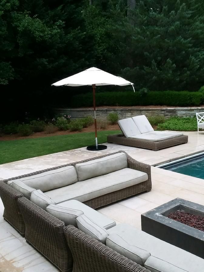 A patio with a couch and umbrella next to a pool