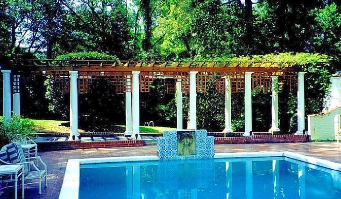 A large swimming pool with a pergola in the background