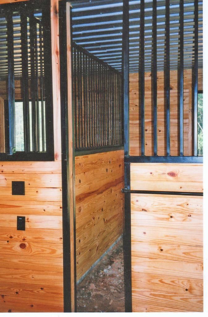 A horse stable with a wooden wall and metal bars