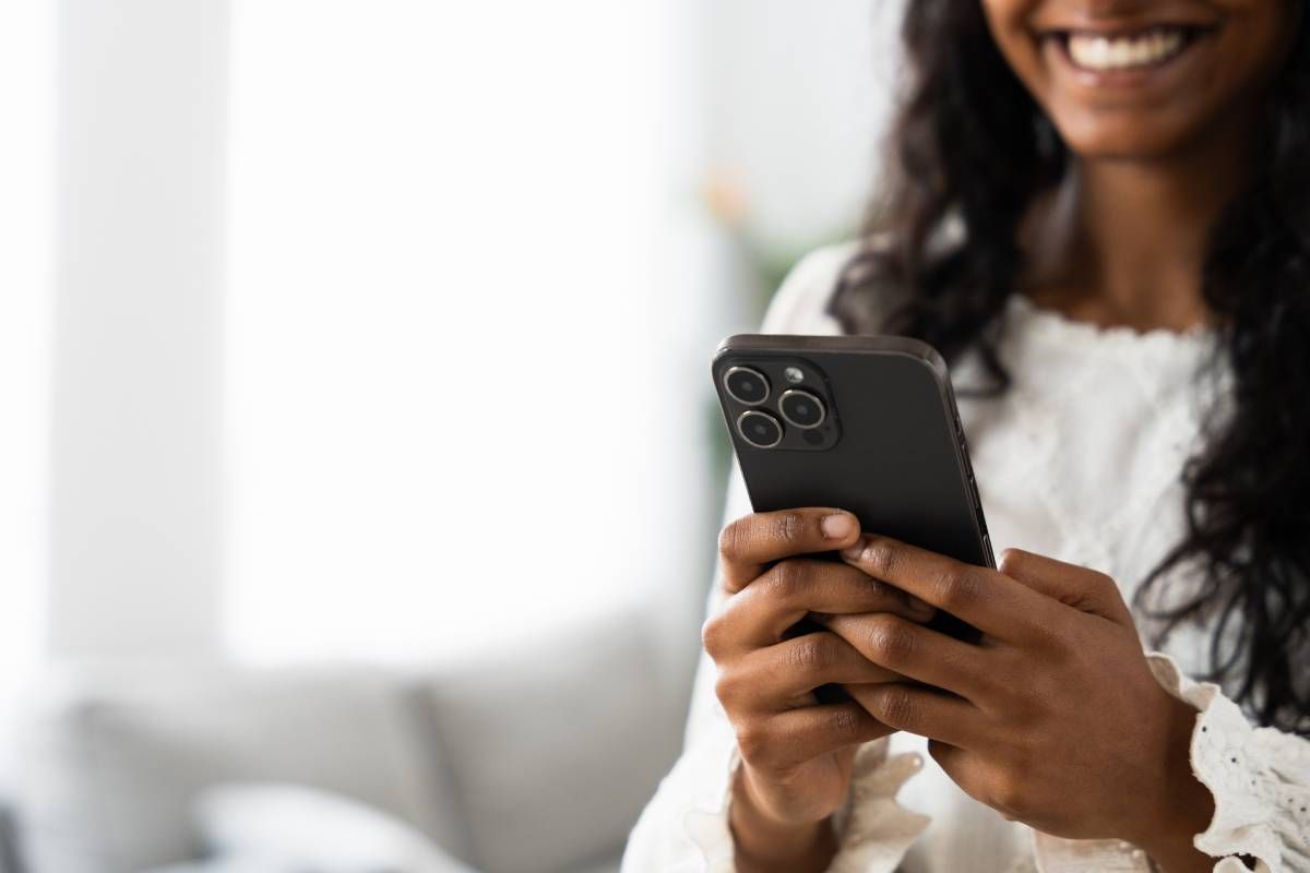 A person using their smartphone to control their motorized window treatments throughout their home