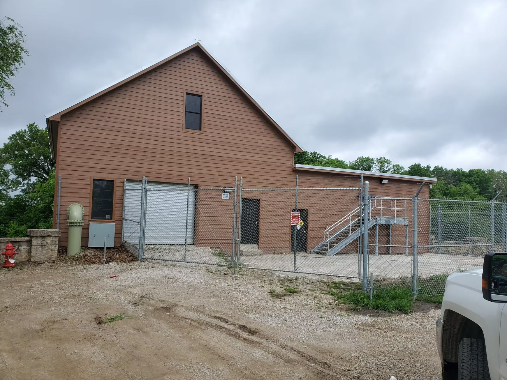 Brick building with a fenced-in area. A truck is parked in front. Overcast day.