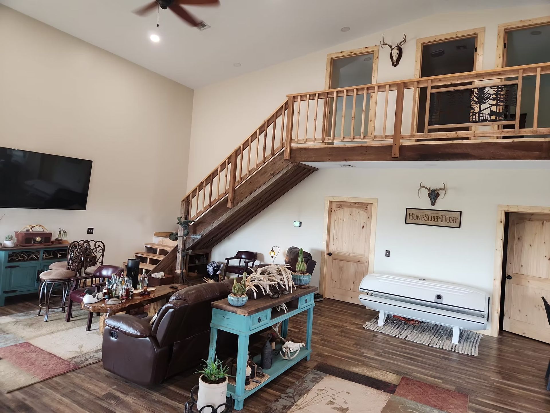 Rustic living room with a staircase leading to a loft area. Features include wooden accents, a leather recliner, \