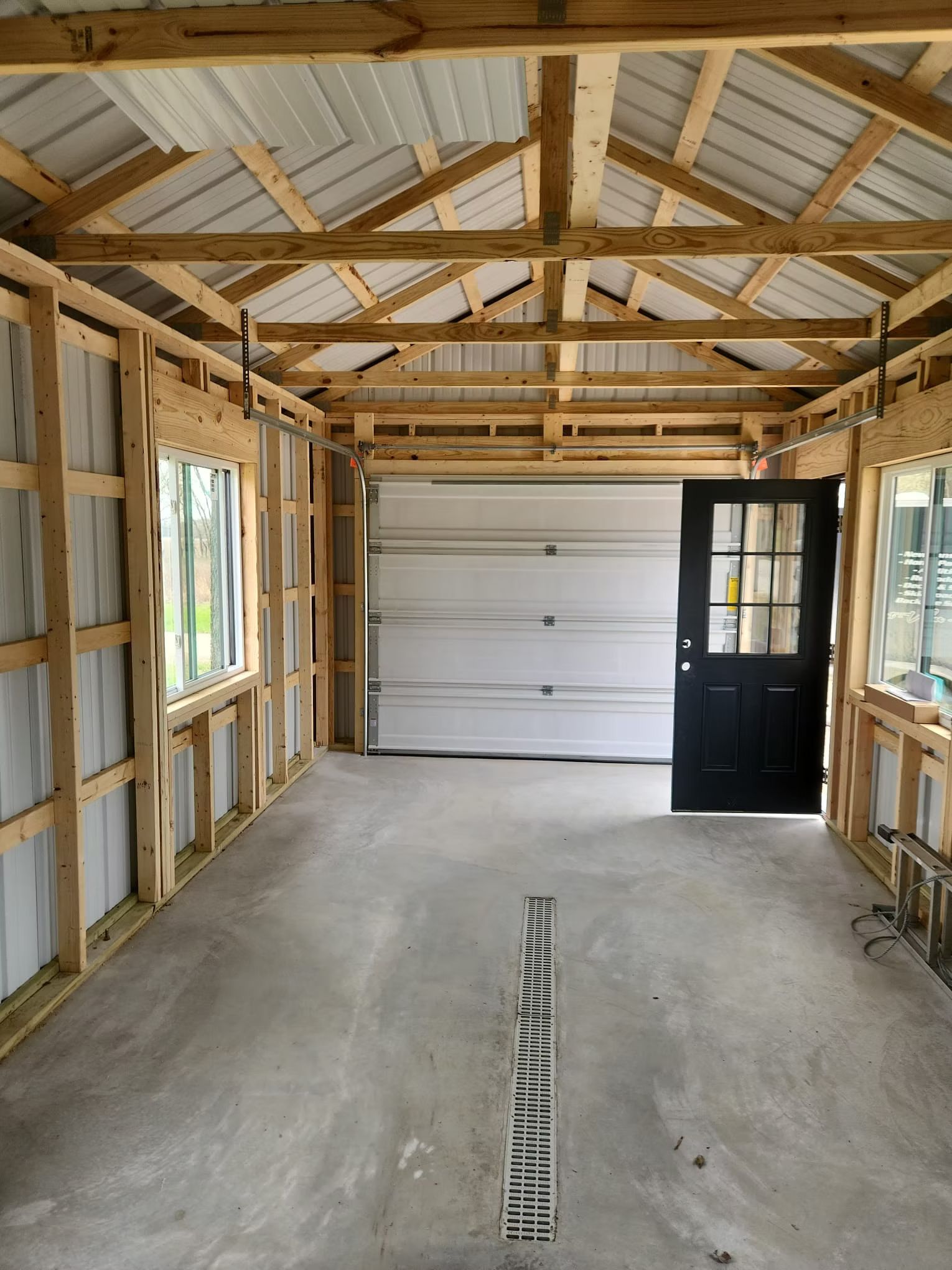 frame, and a white garage door. A black door and windows are also visible.