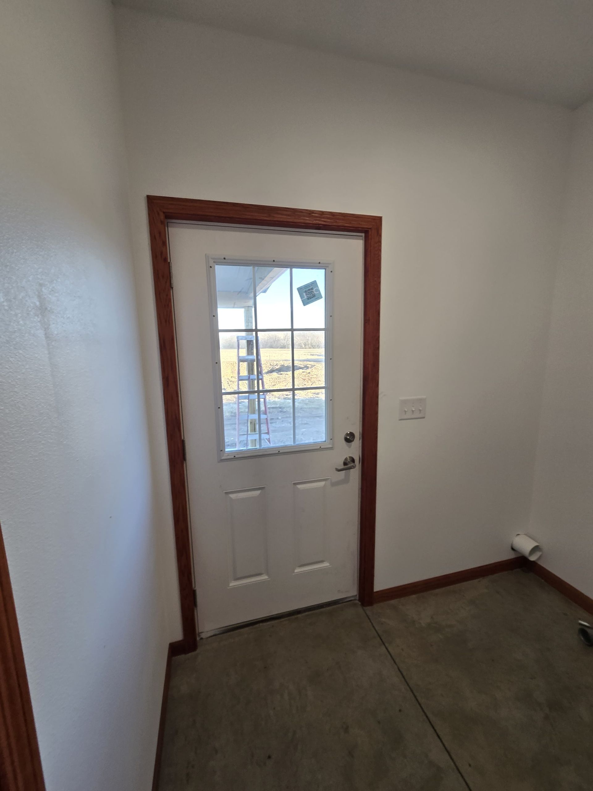 Wooden frame of a building under construction, with a high roof structure, set against a bright sunlit sky.
