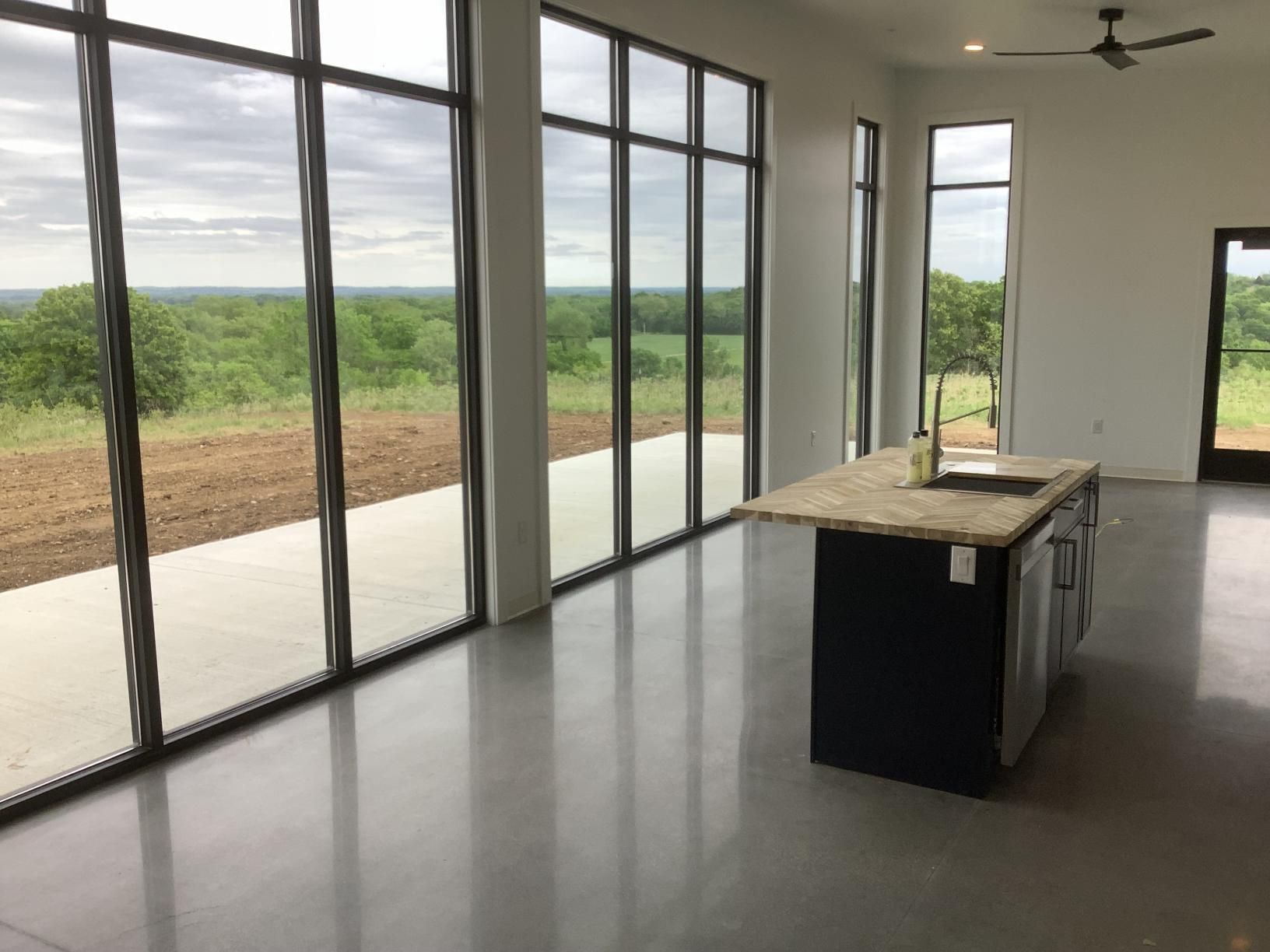 Empty modern kitchen with floor-to-ceiling windows overlooking a green landscape