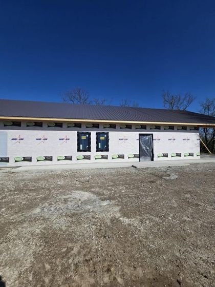 A newly constructed one-story building with dark gray siding, a stone-