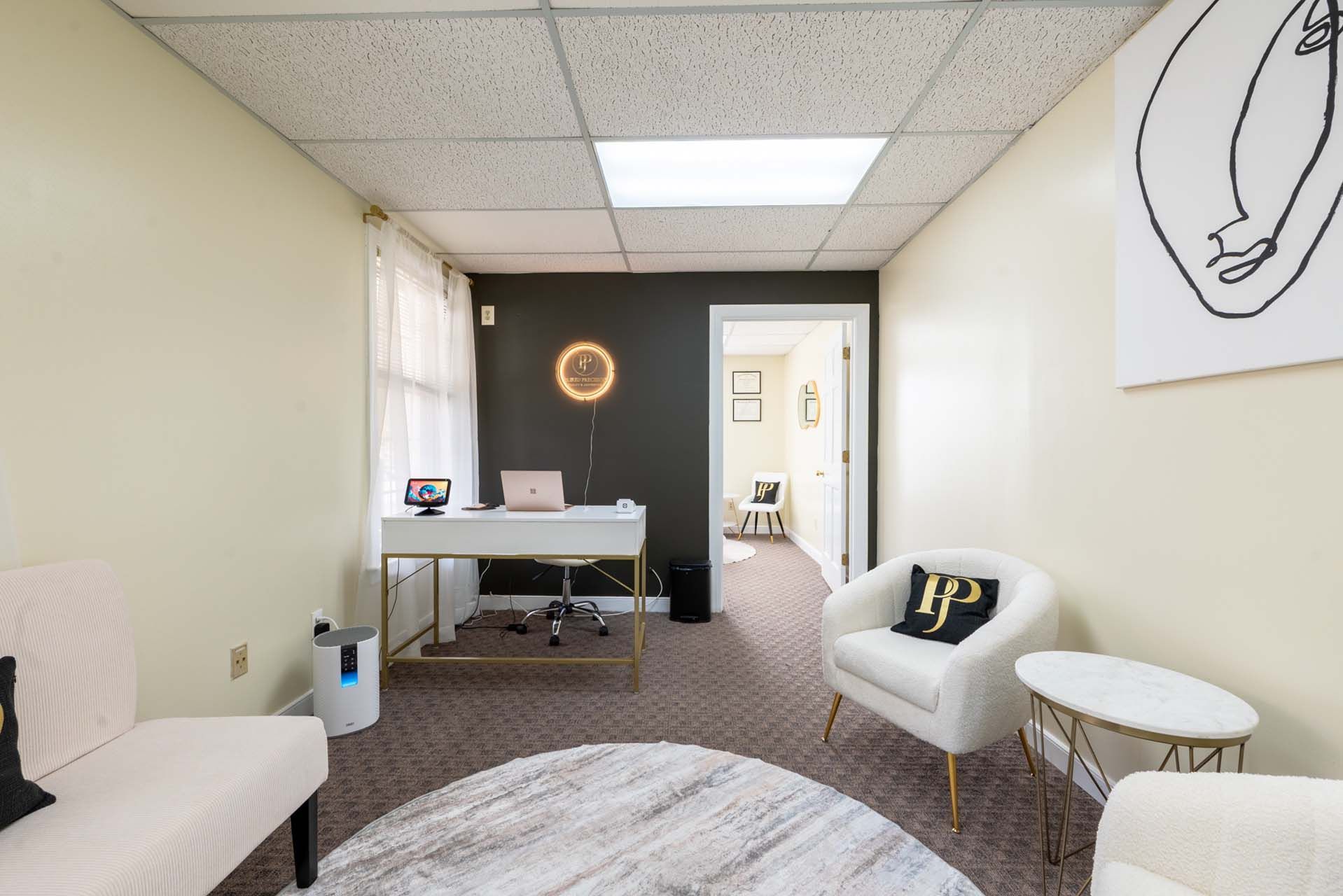 Office interior with a desk, chairs, rug, and artwork. Neutral colors with modern decor.