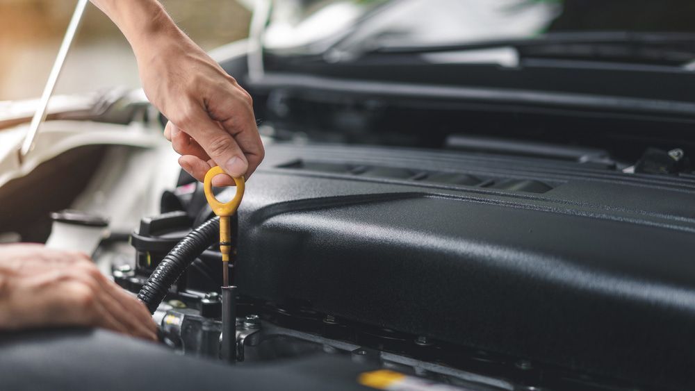 A Person Is Checking The Oil Level In A Car Engine — Carson's Car Care In Armidale, NSW