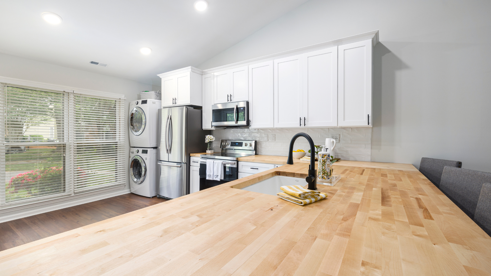 Modern kitchen with white cabinets, stainless steel appliances, and wood countertops.