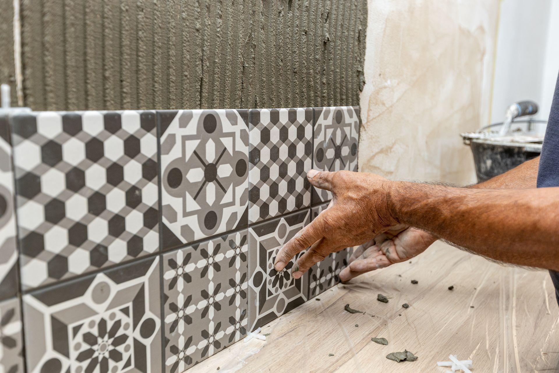 Person installing patterned tiles on a wall.