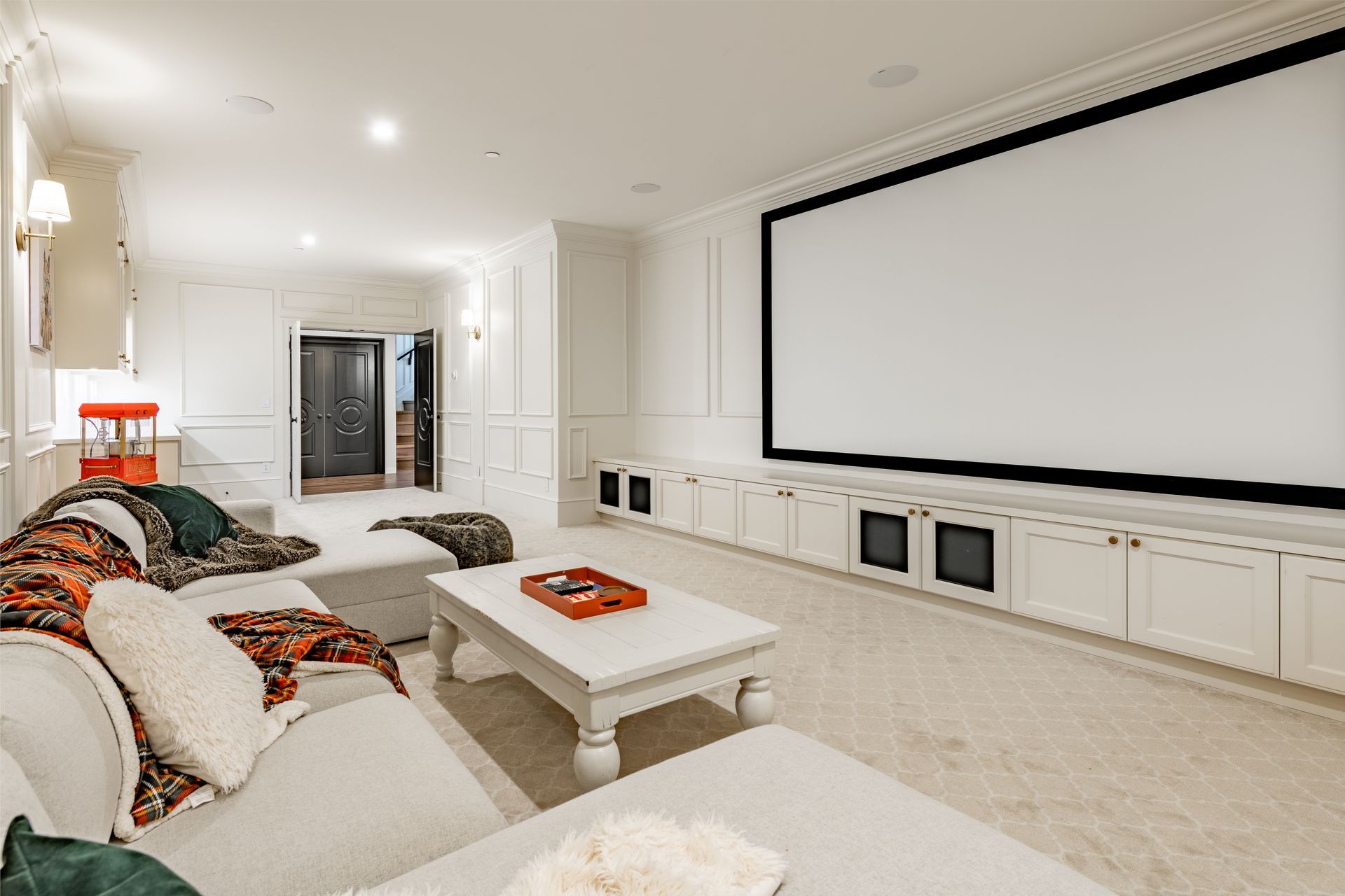 Home theater with a large white screen, white cabinets, and a white sectional sofa.