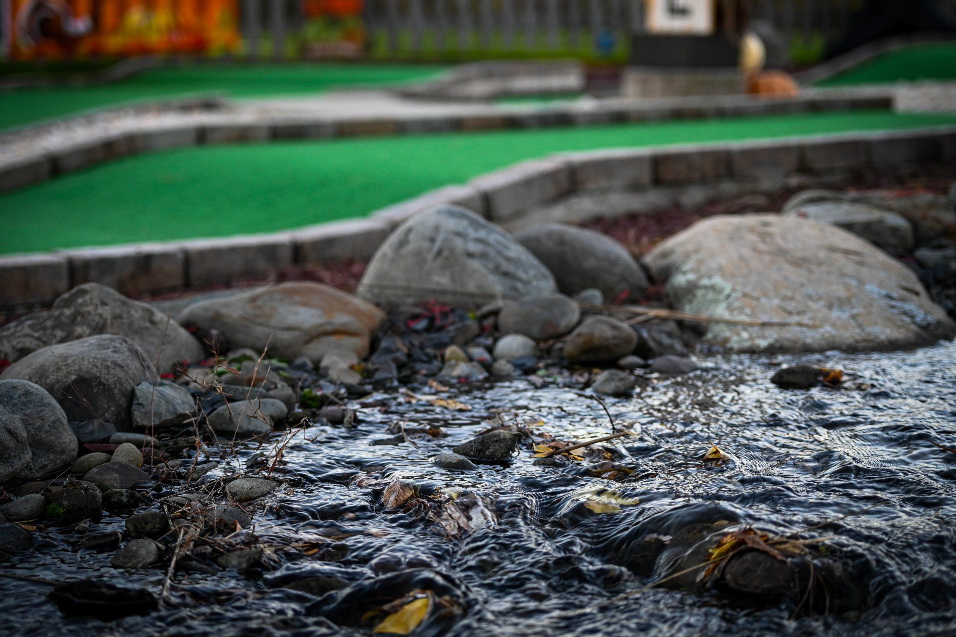 A small stream running through a rocky area next to a golf course.