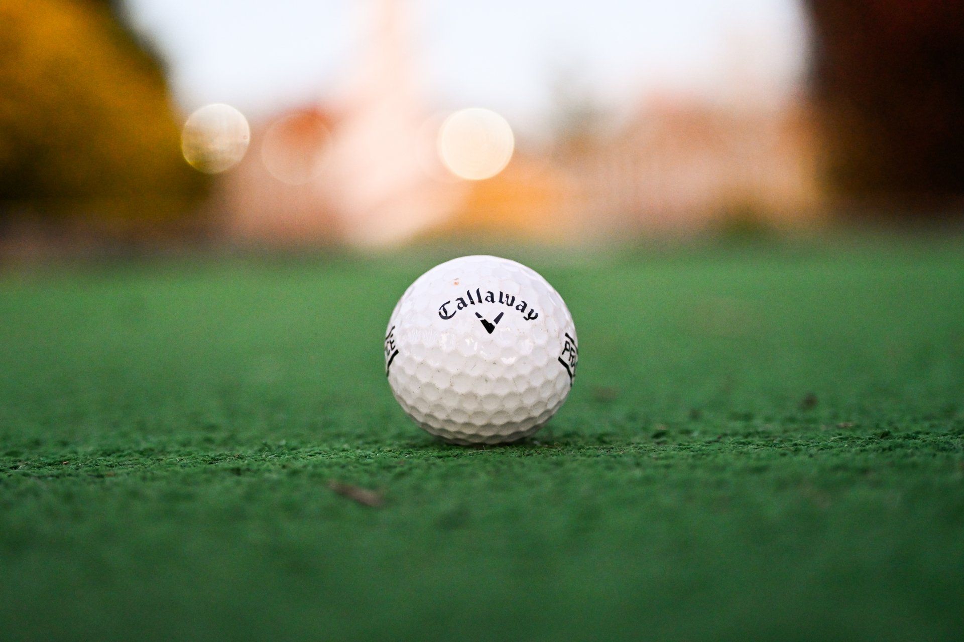 A white golf ball is sitting on top of a green golf course.