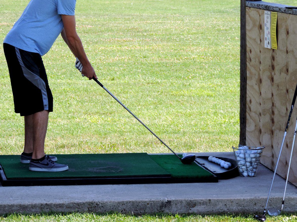 A man is swinging a golf club at a golf ball