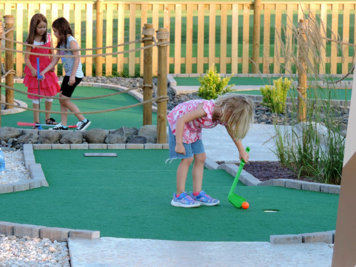 A little girl is playing a game of mini golf
