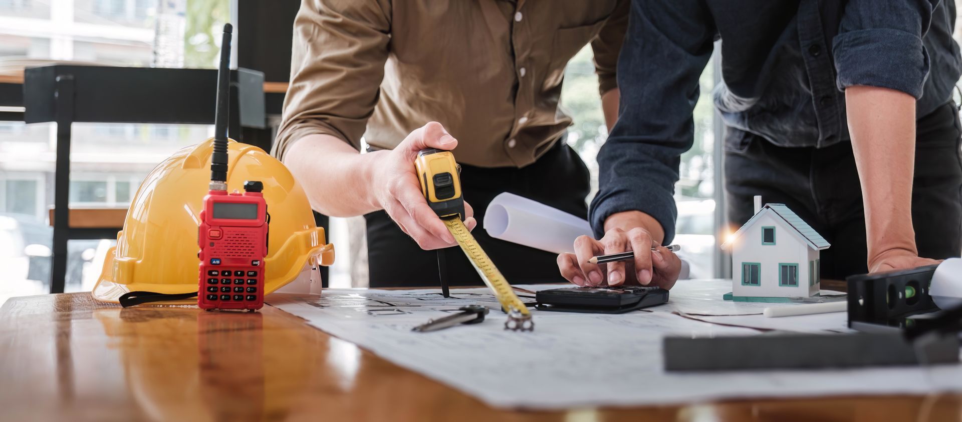 A couple of men are standing around a table looking at a blueprint.