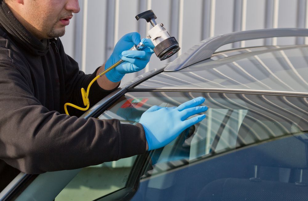 Person Repairing Windshield of a Car Using a Tool, Wearing Gloves — Southern Tablelands Windscreen Repairs in Goulburn, NSW