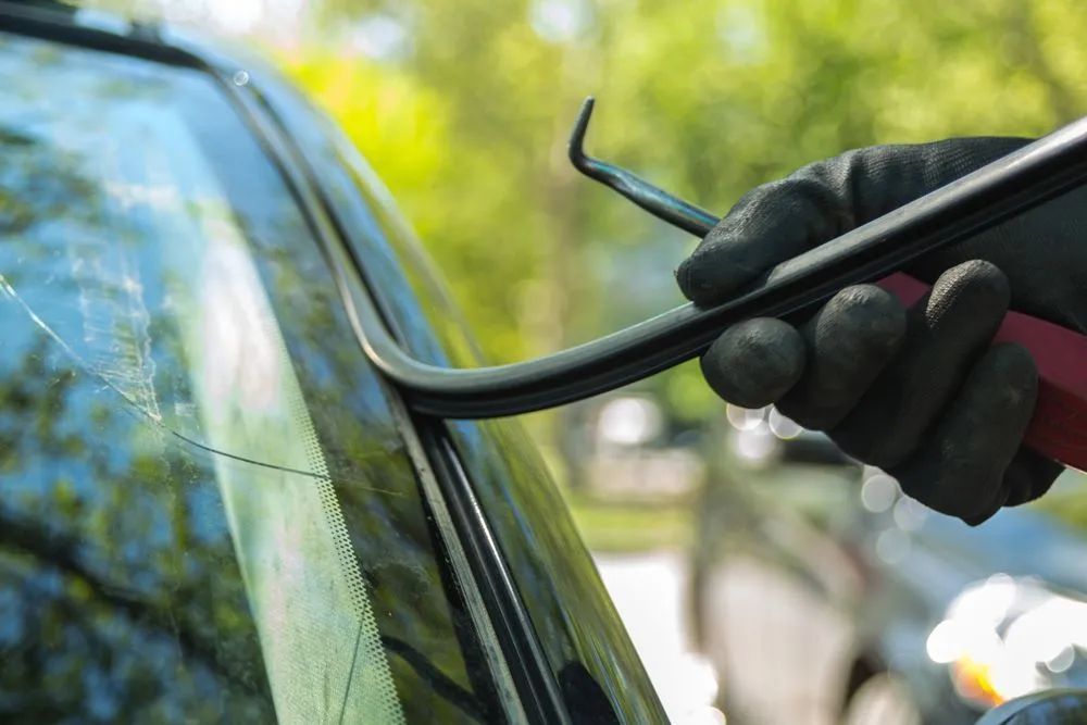 Gloved Hand Uses a Tool to Pry Away a Black Rubber Seal — Southern Tablelands Windscreen Repairs in Bowral, NSW