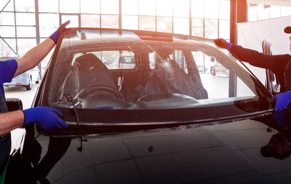 Two Workers Installing a Windshield on a Black Car in a Garage — Southern Tablelands Windscreen Repairs in Crookwell, NSW