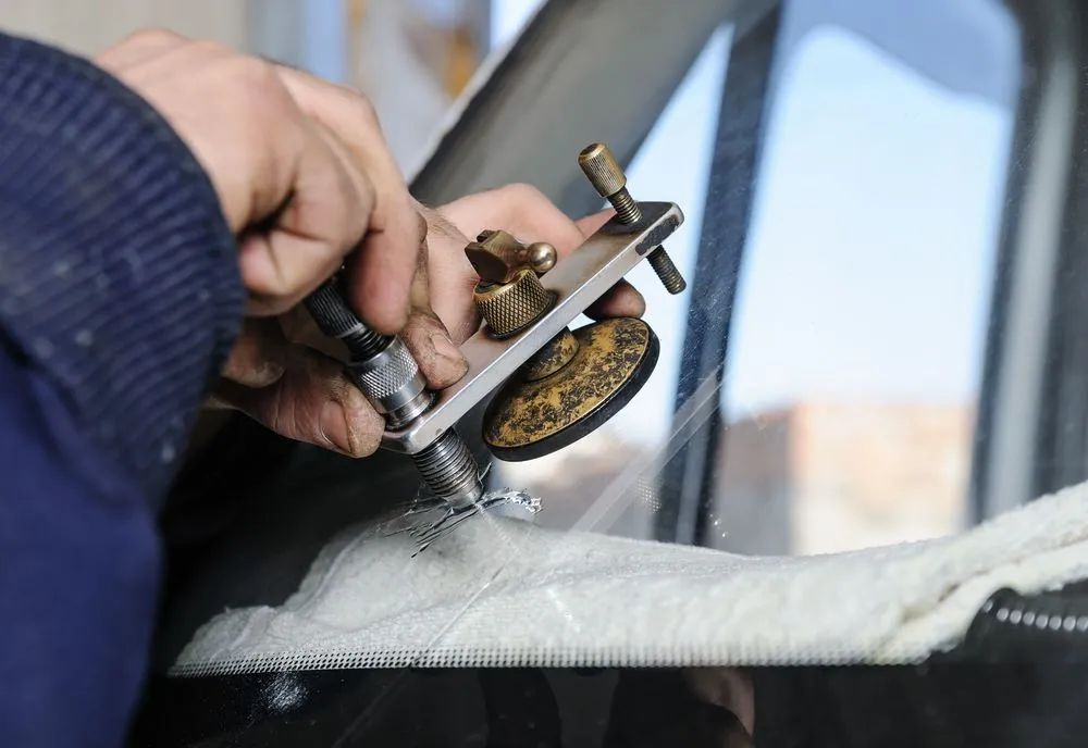 A Person Using a Tool to Repair a Crack in a Car Windshield — Southern Tablelands Windscreen Repairs in Taralga, NSW