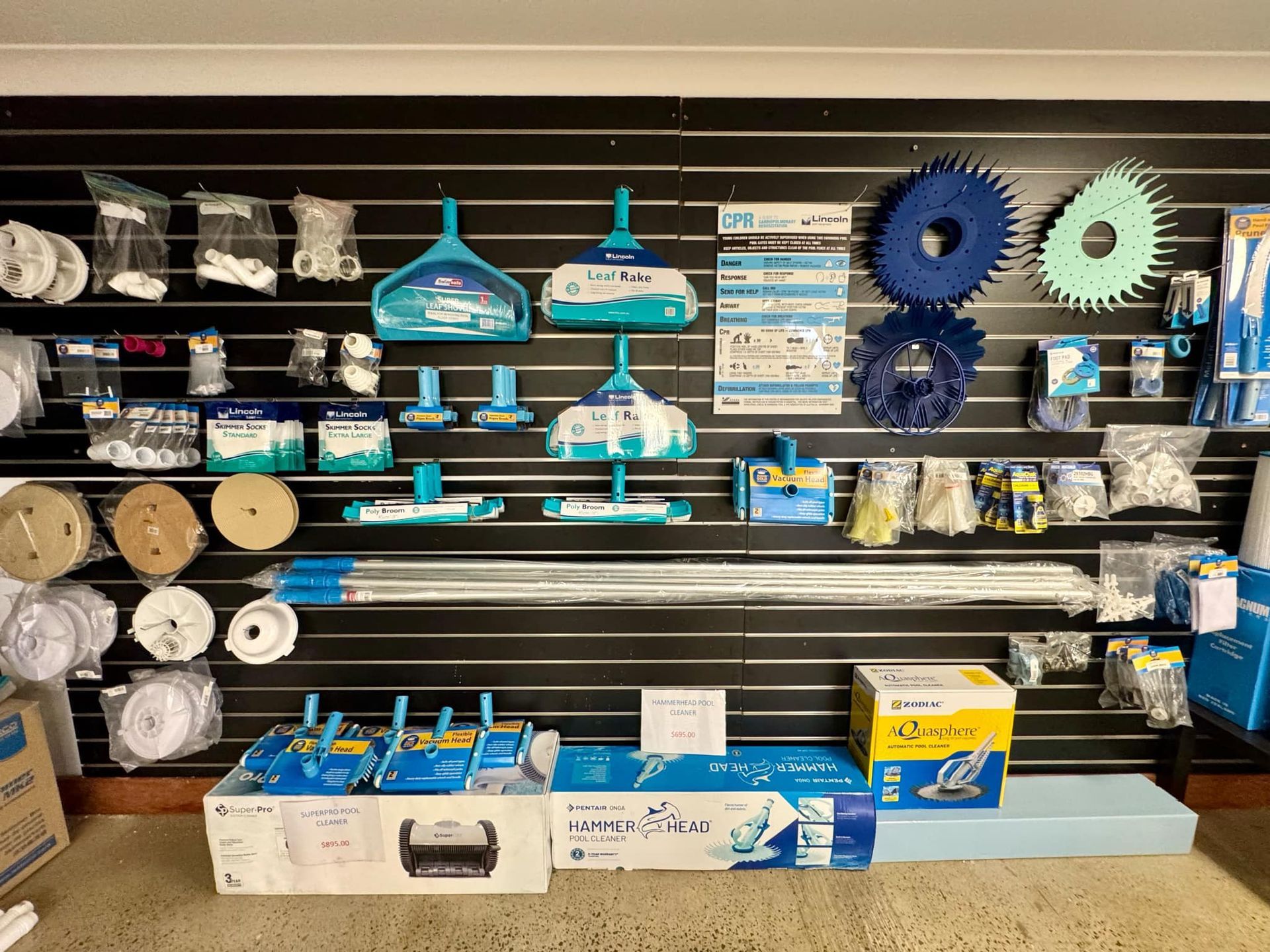 Pool supplies displayed on a black wall, featuring blue, white, and yellow equipment and accessories — Tweed Pool Shop in Tweed Heads South, NSW