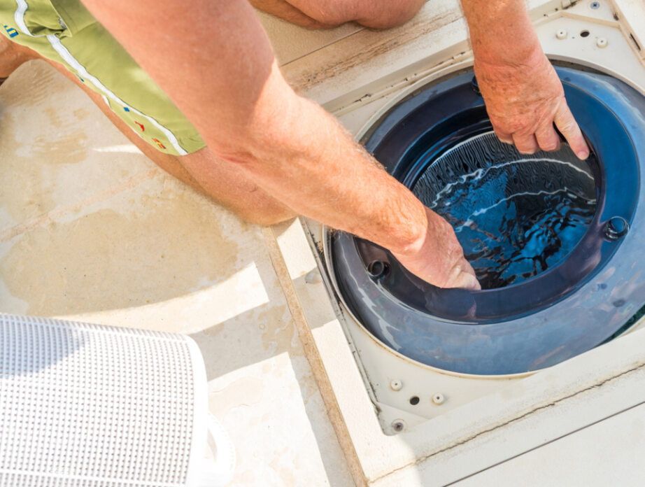 A Man is Cleaning a Swimming Pool With His Hands — Tweed Pool Shop in Casuarina, NSW