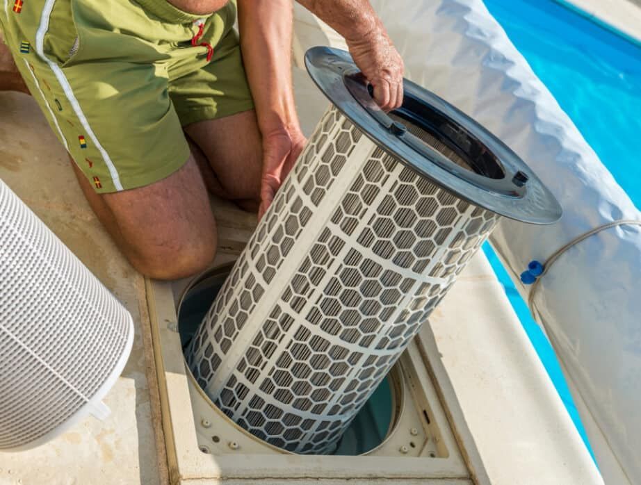A Man is Kneeling Down to Remove a Filter From a Swimming Pool — Tweed Pool Shop in Tweed Heads South, NSW