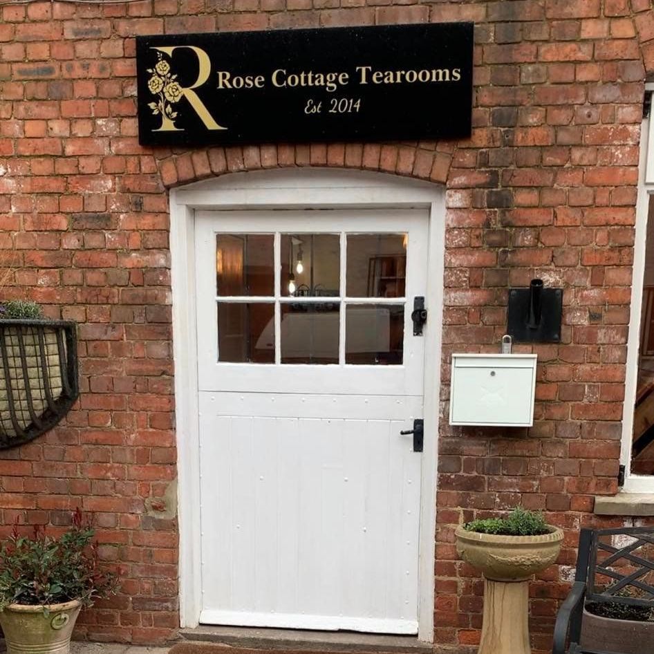 A white door with a sign above it that says rose cottage tearooms