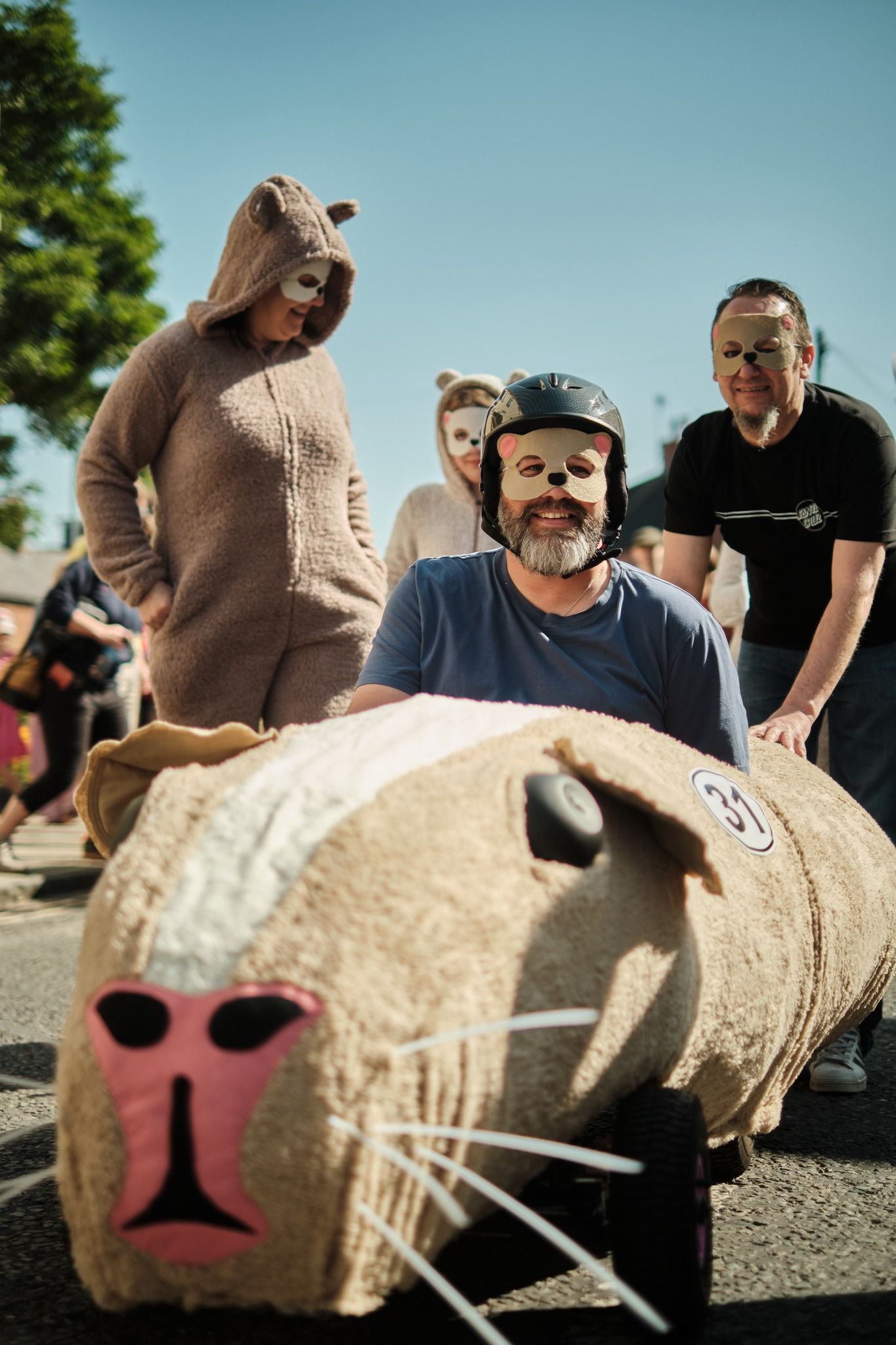 A man wearing a mask is driving a sheep shaped car.