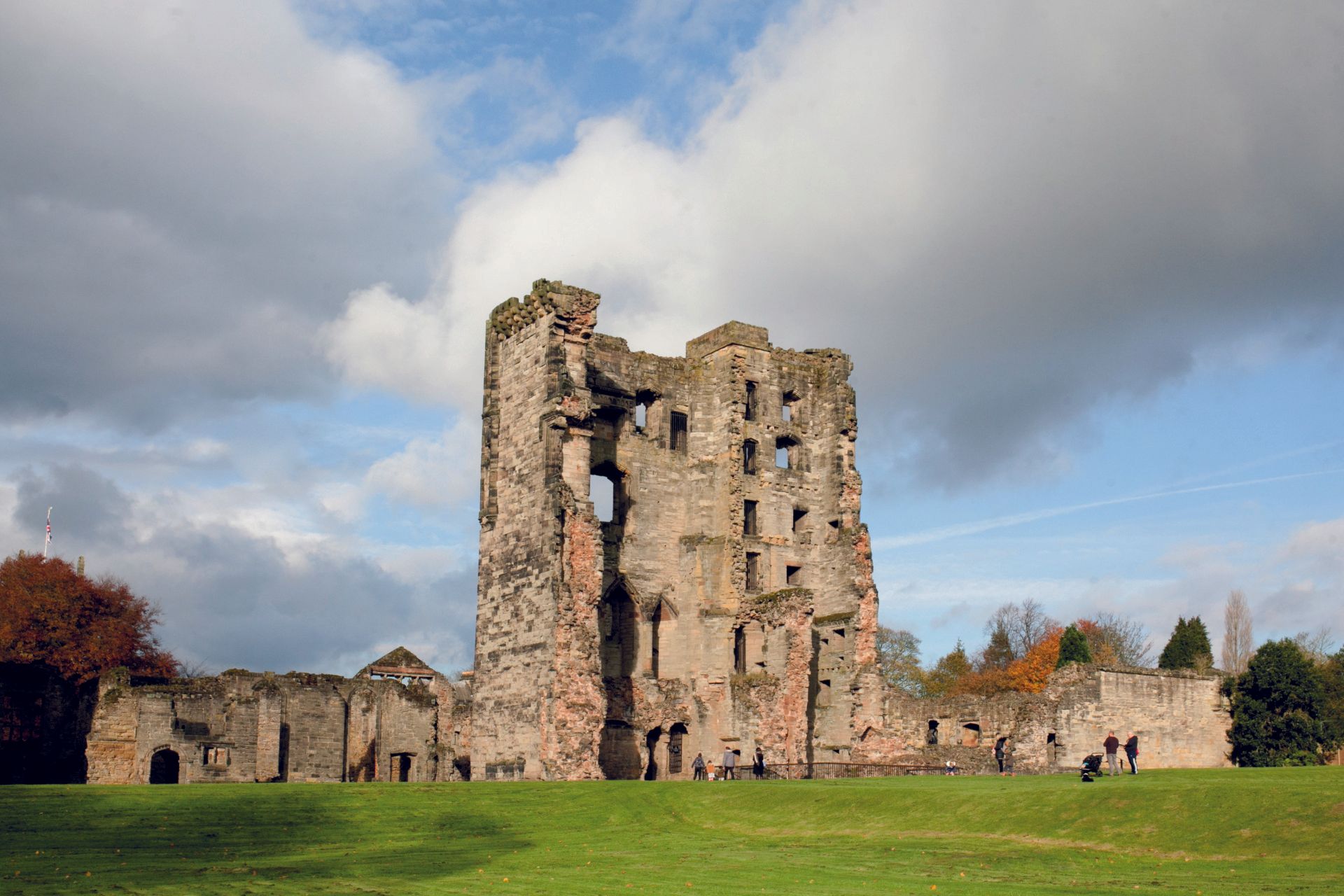 A large stone castle is sitting in the middle of a grassy field.