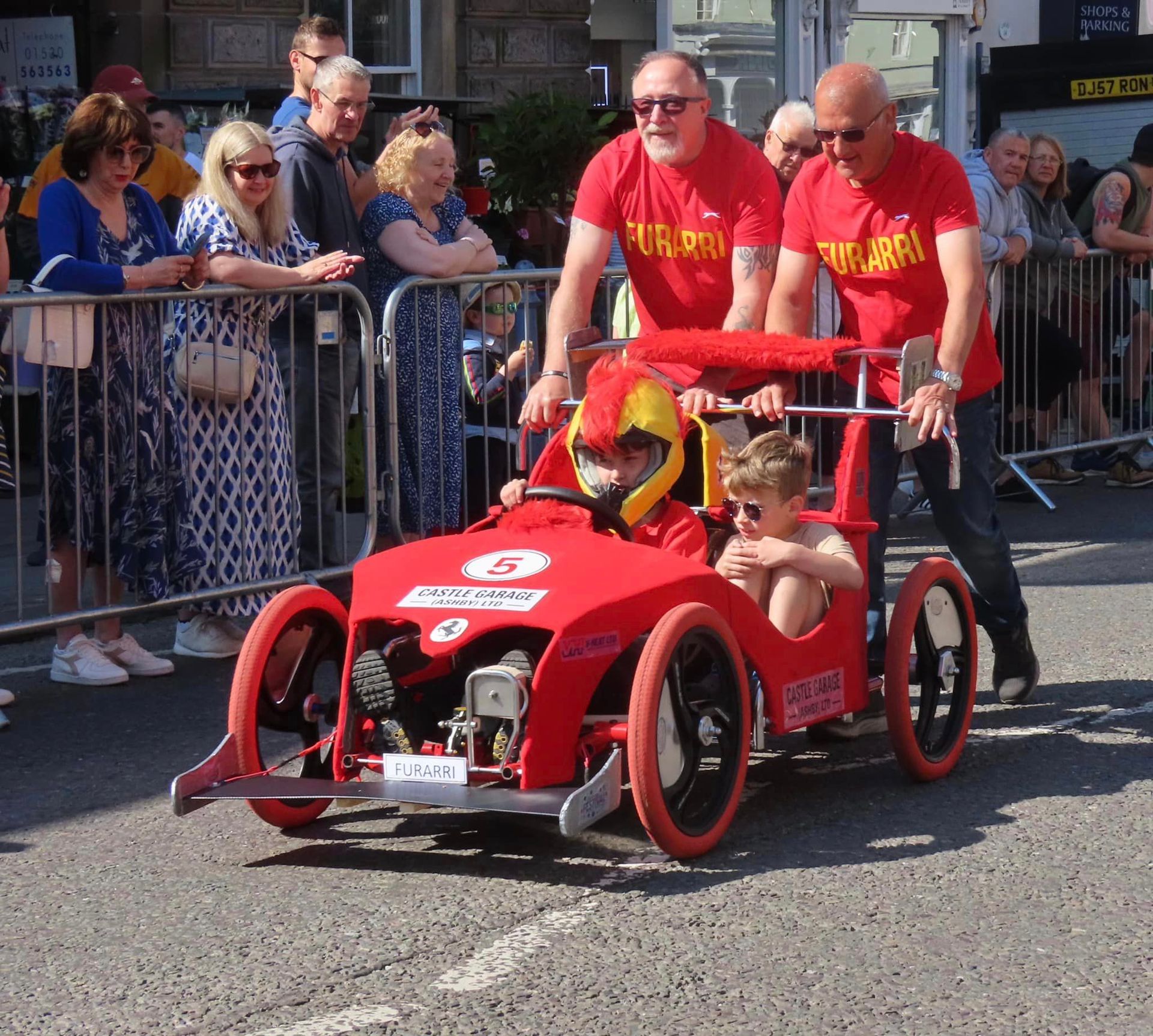 A group of people standing around a red car with the number 4 on it