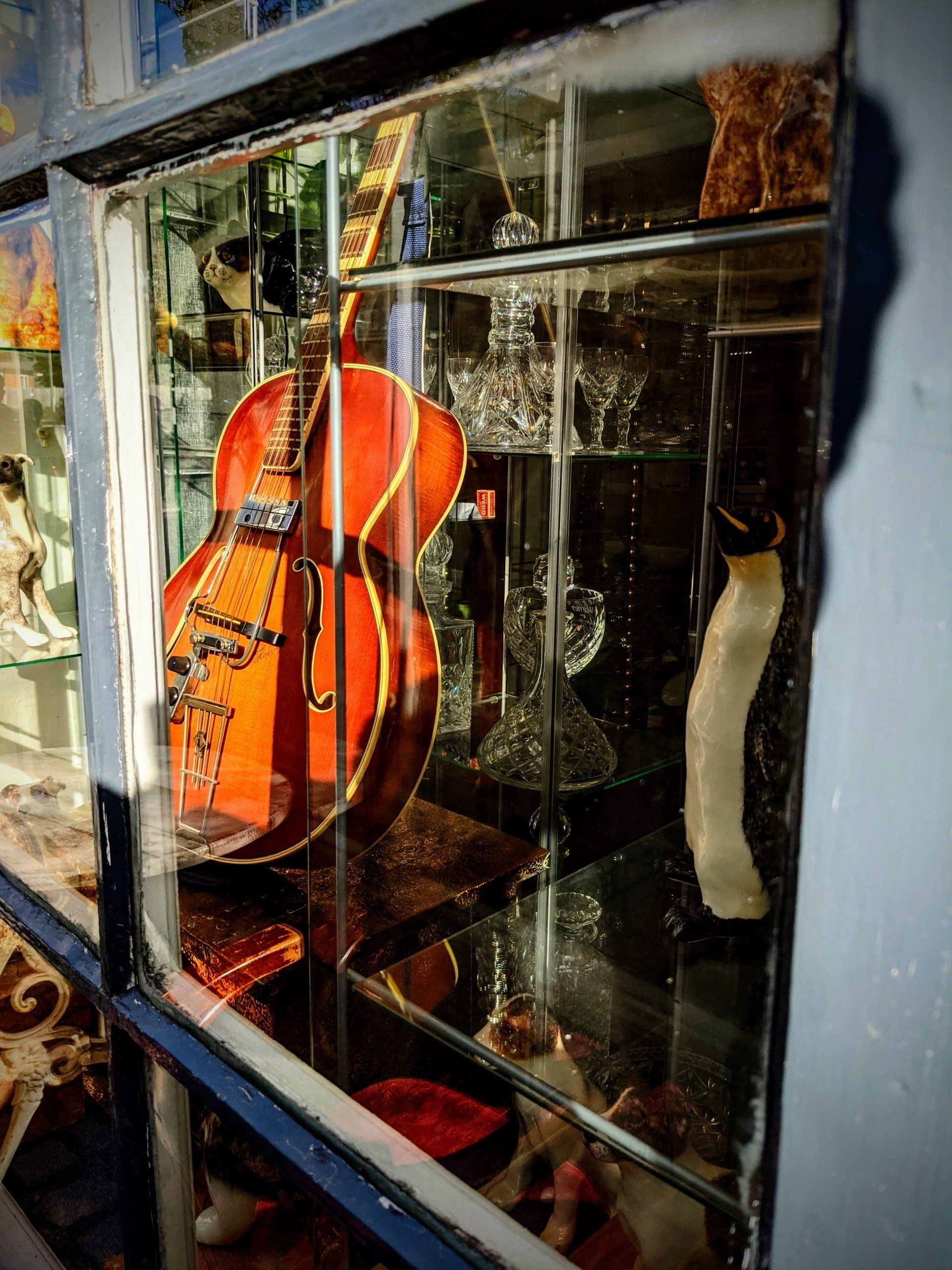 A guitar is displayed in a glass case in a window