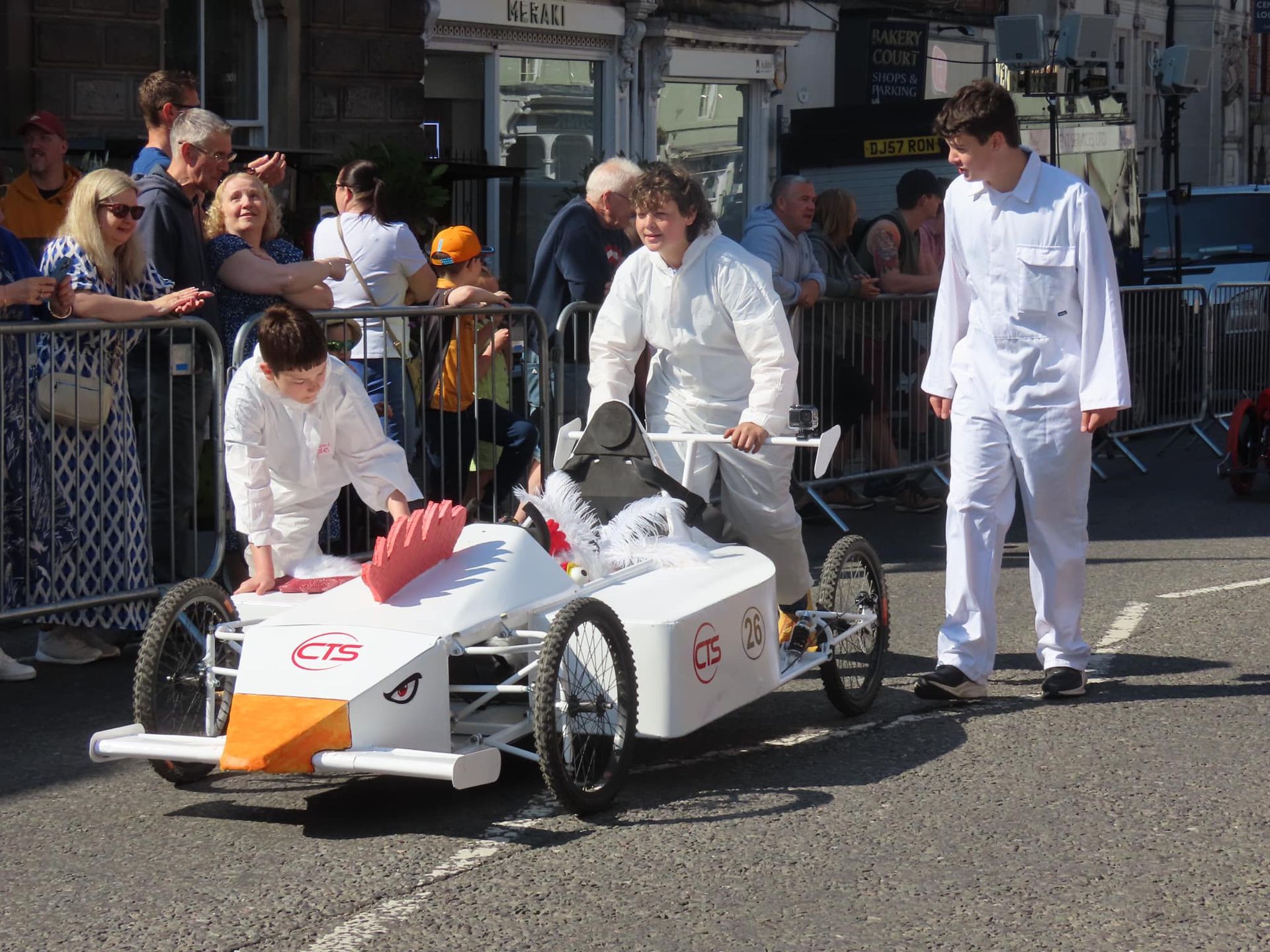 A group of people in white overalls are standing around a race car