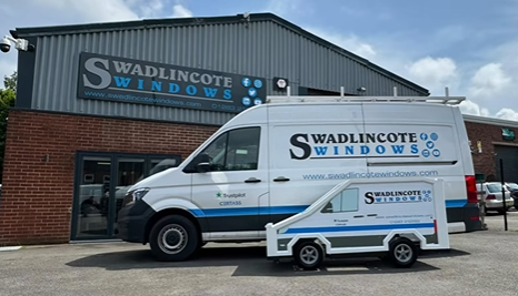 A white van is parked in front of a building that says swadlingcote windows.