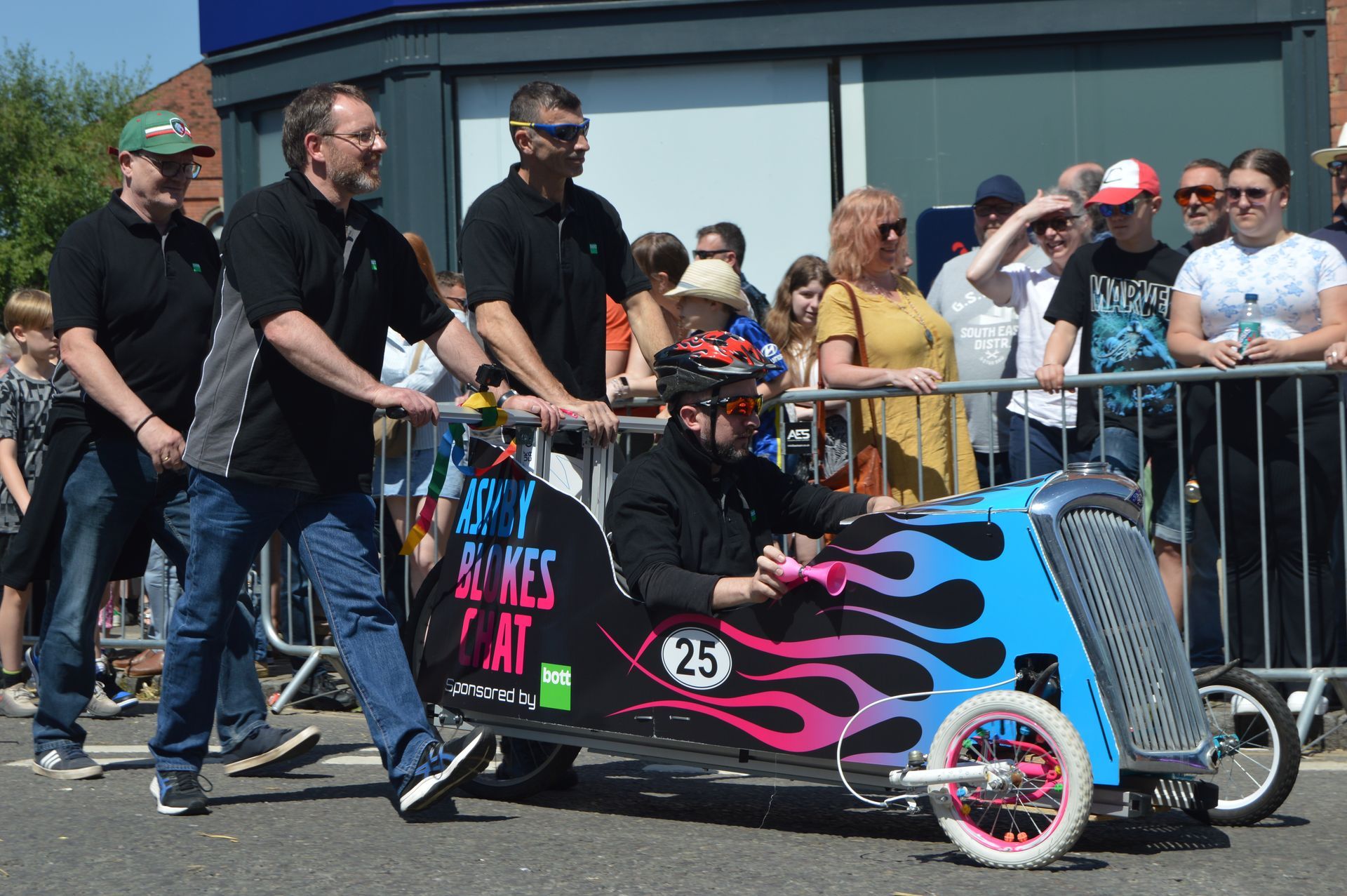 A group of men are pushing a go kart down a street.