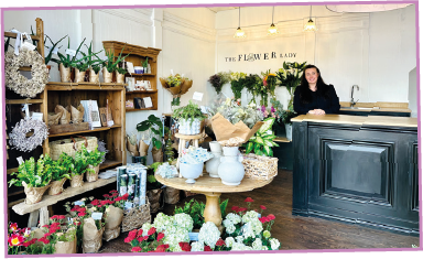 A woman is sitting at a counter in a flower shop.