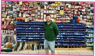 A man is standing in front of a wall of shelves in a hardware store.