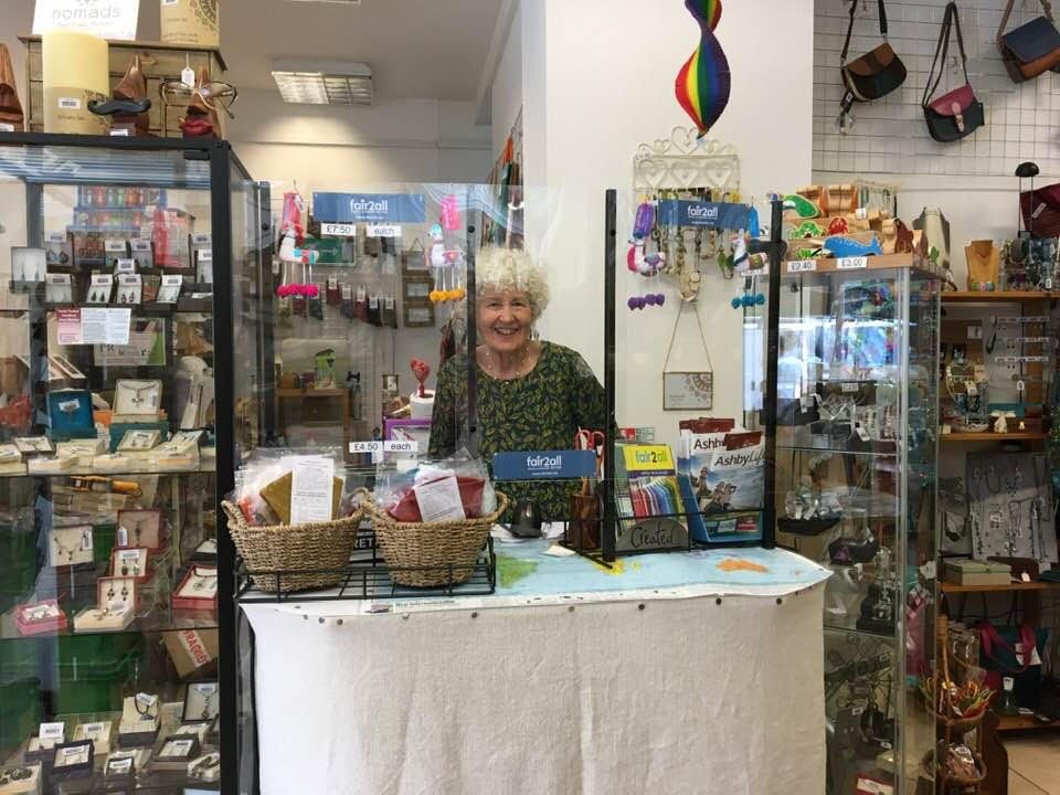 A woman is standing behind a counter in a store.