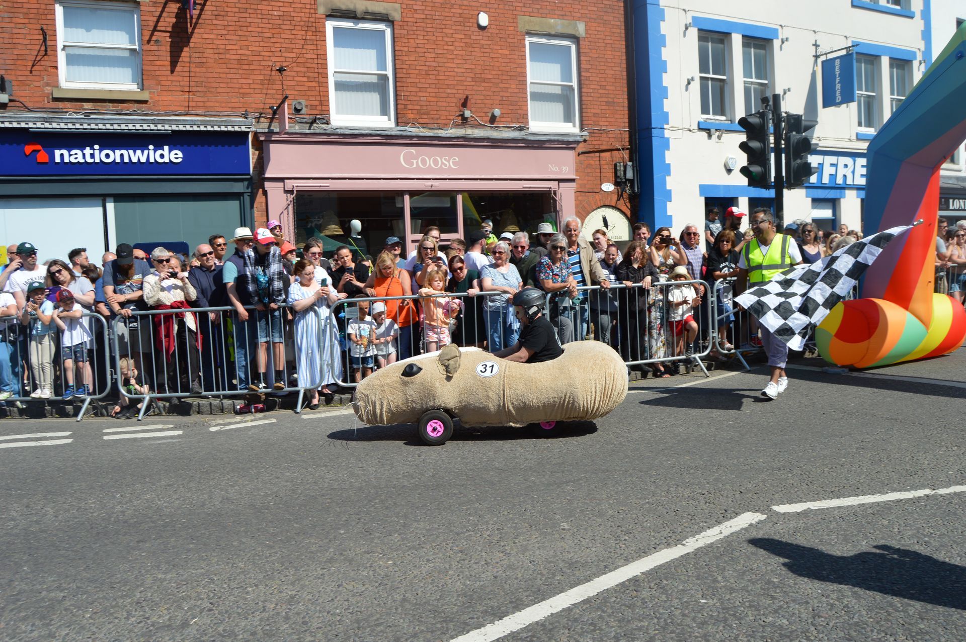 A man is driving a sheep car down a street in front of a nationwide store