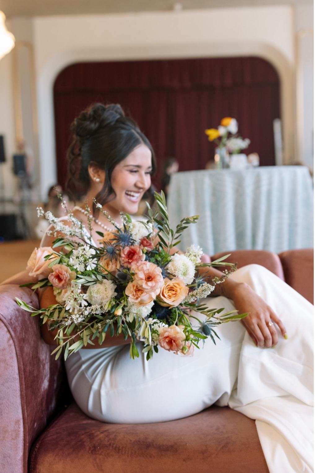 Couple kissing in front of a red barn with two donkeys adorned with floral arrangements.